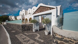 Un edificio de fachada de piedra, paredes blancas y entrada con tejas.