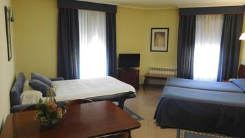 A hotel room with two beds, a desk, a chair, a TV, and a framed picture on the wall.