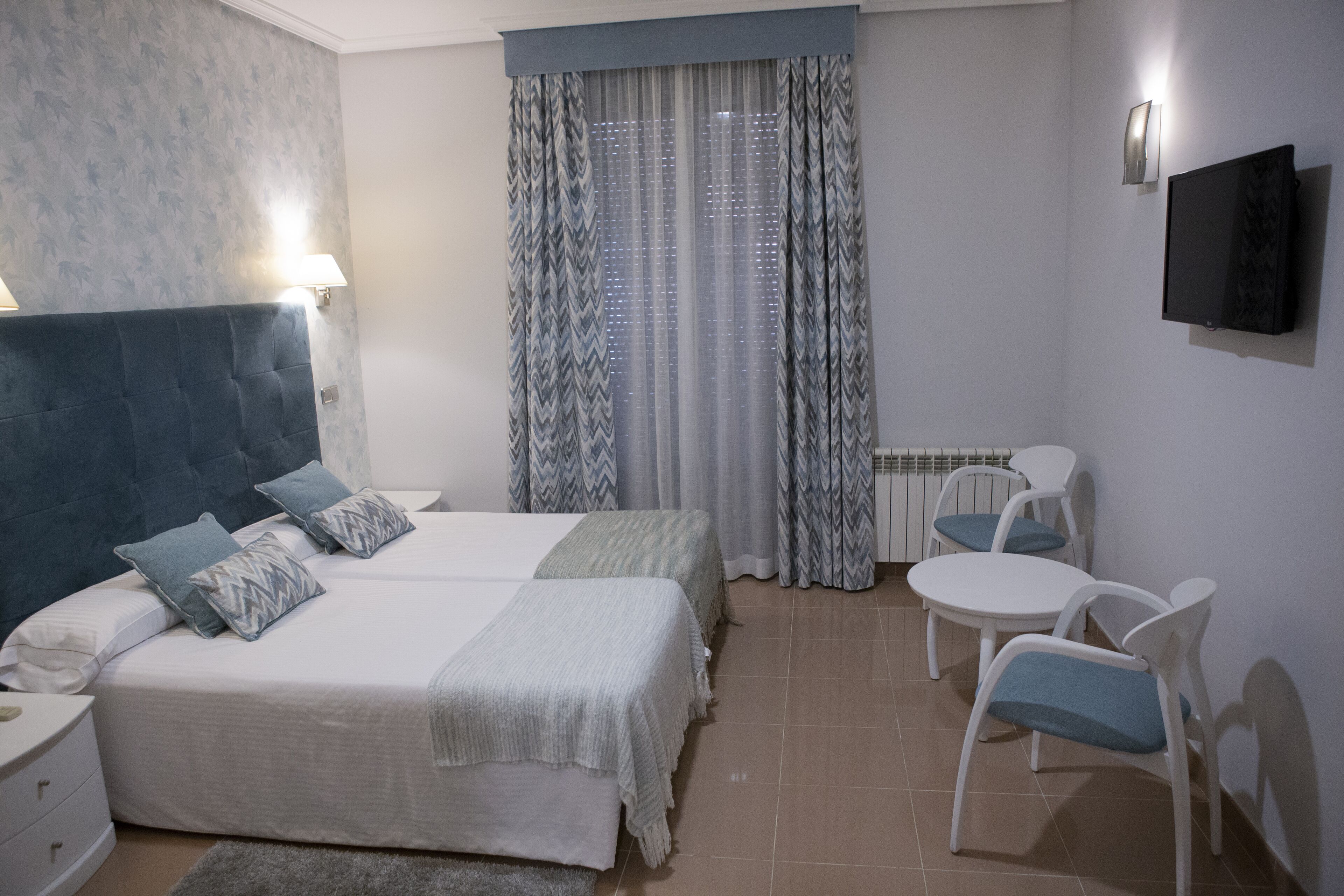 A bedroom with two beds, a desk, and a chair.