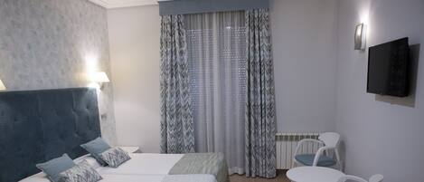 A bedroom with two beds, a desk, and a chair.