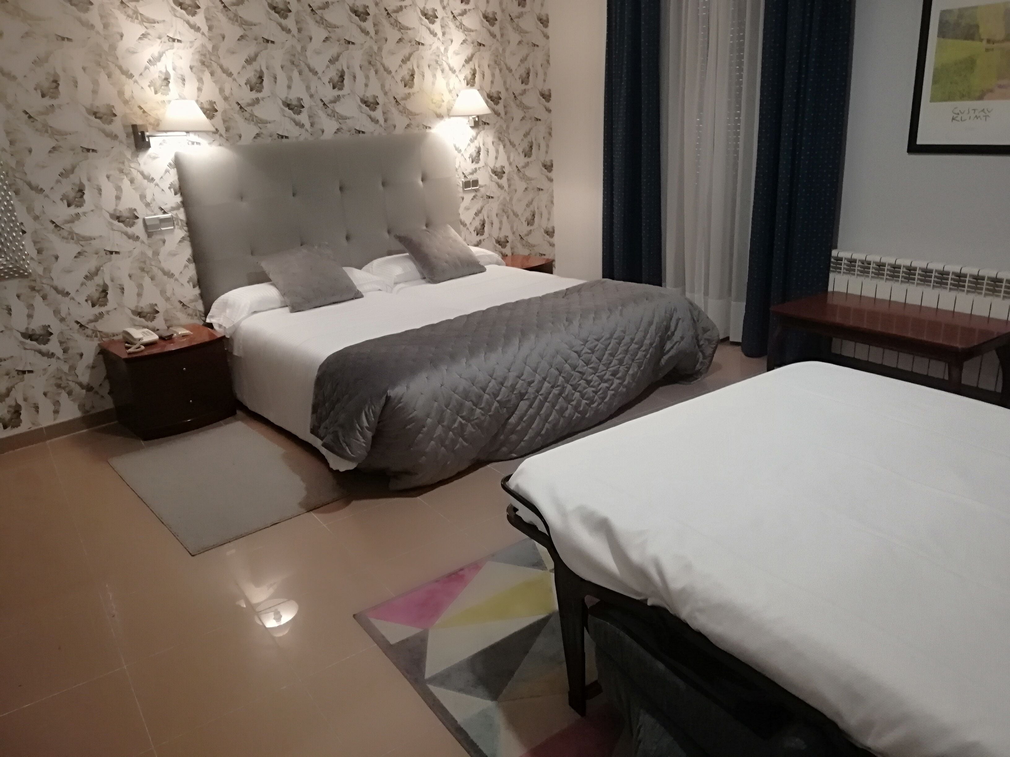 A bedroom with a bed, a bedside table, a lamp, and a wall-mounted artwork.