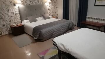 A bedroom with a bed, a bedside table, a lamp, and a wall-mounted artwork.