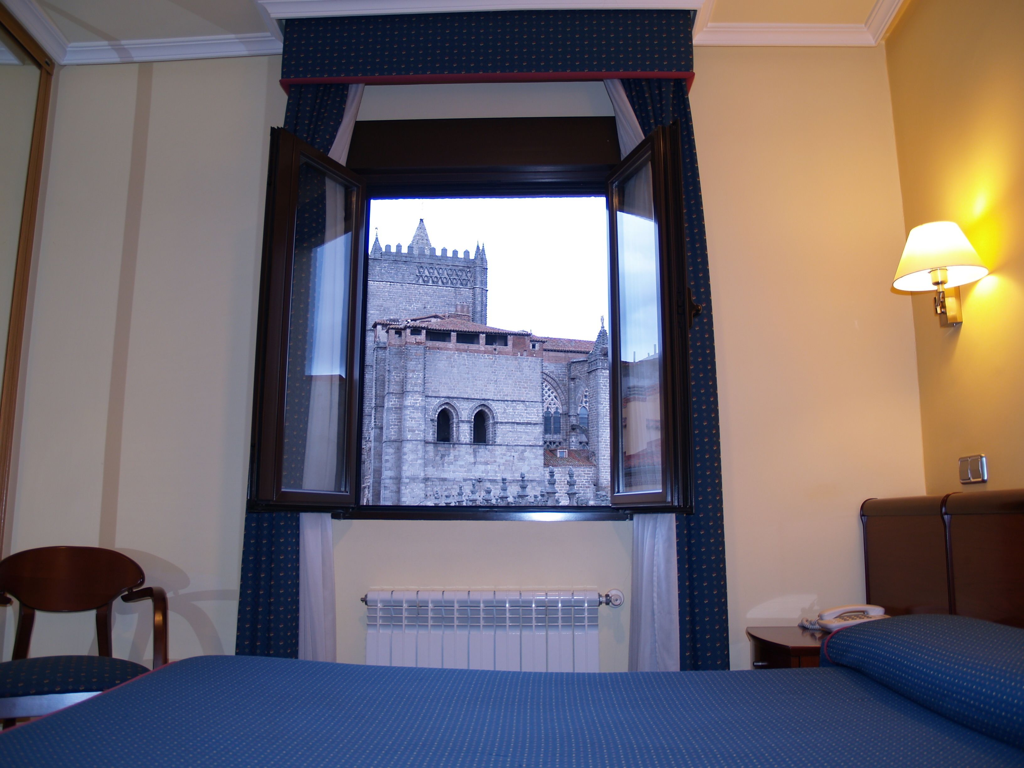 Una habitación de hotel con un ventanal que ofrece vistas a un edificio histórico.