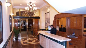 A hotel lobby with a marble reception desk, a chandelier, and a large mirror. - Hotel Las Moradas (Ávila)