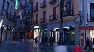 Una plaza con una fuente, rodeada de edificios con balcones y un letrero de hotel.