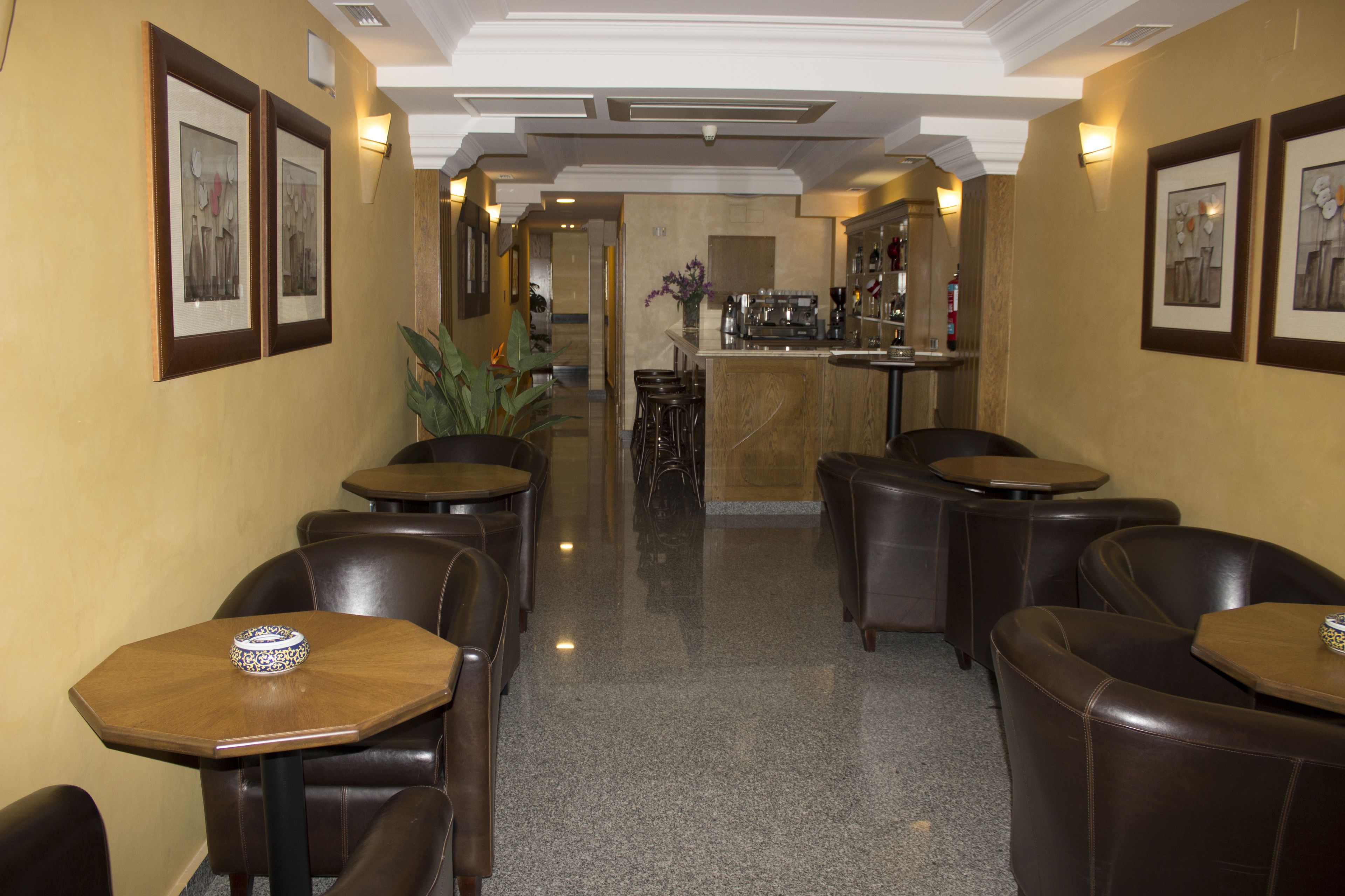 Un hall de hotel con zona de bar, arreglos de asientos y obras de arte enmarcadas en las paredes.