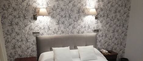 Une chambre à coucher avec un lit, deux lampes de chevet, une table de chevet et une poubelle.