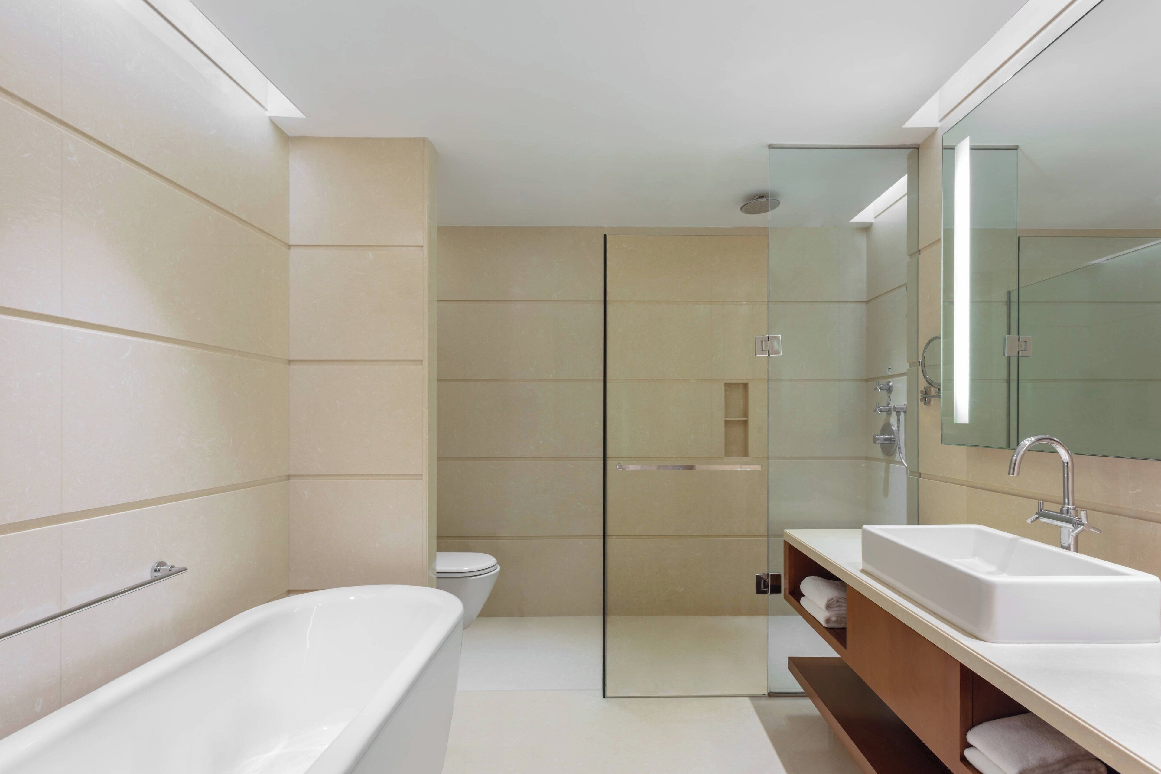 A modern bathroom with a bathtub, a glass-enclosed shower, and a vanity with a sink.