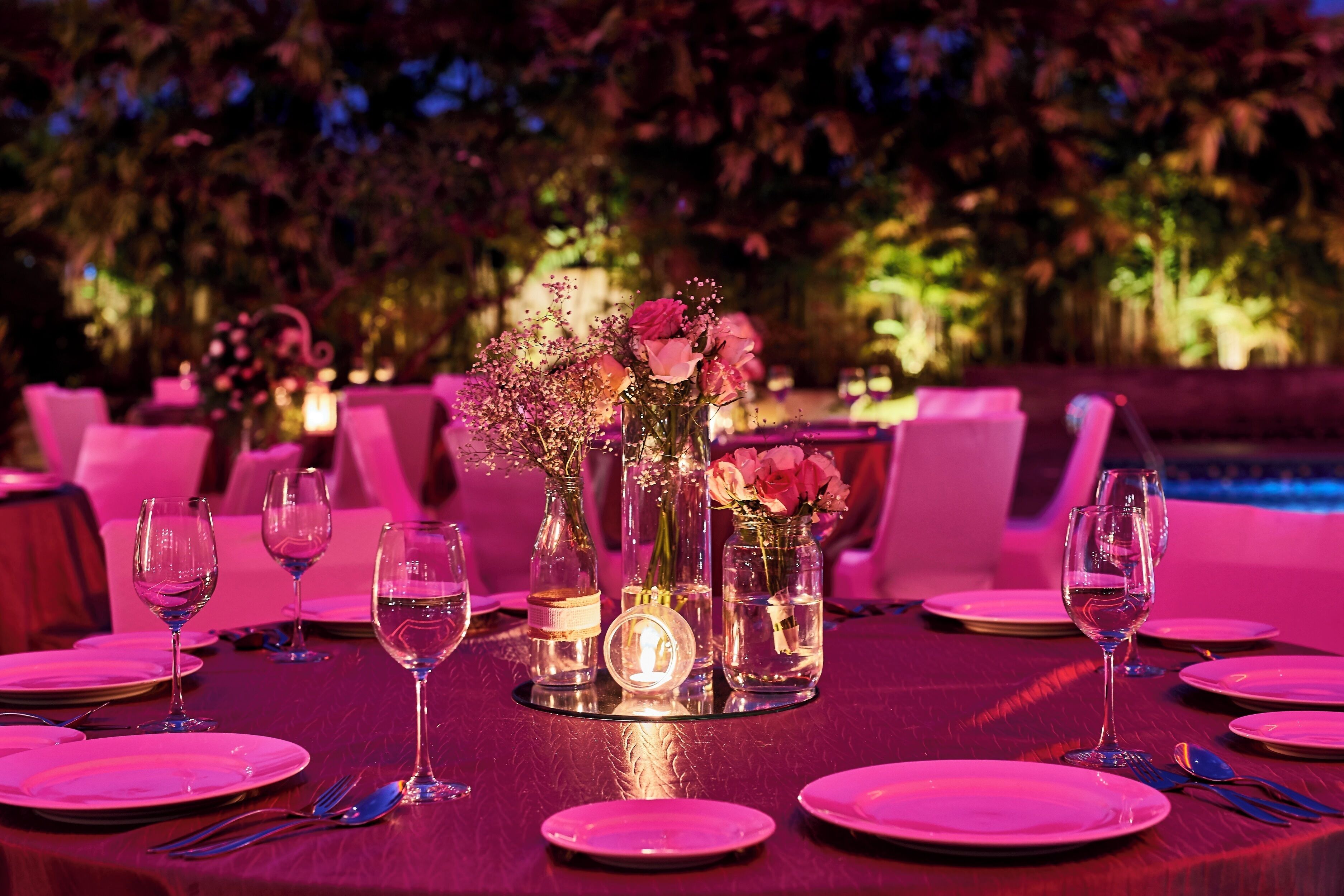 A table set for a meal with glassware, plates, and a candle centerpiece.