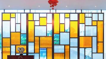 A modern interior with a large, abstract stained glass window, a unique chandelier, and contemporary red chairs.