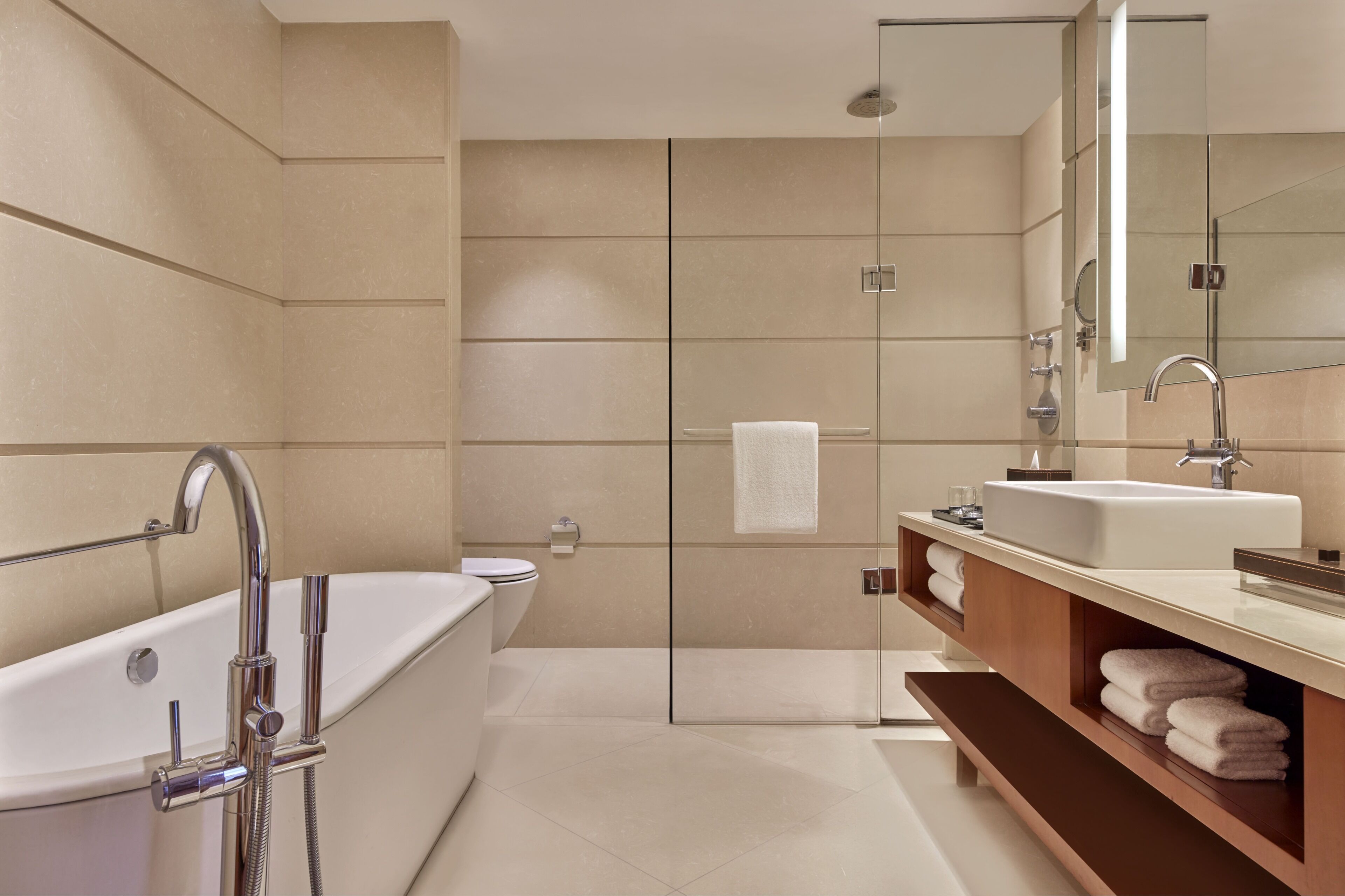A modern bathroom with a bathtub, a shower, a vanity with a mirror, and a towel rack.