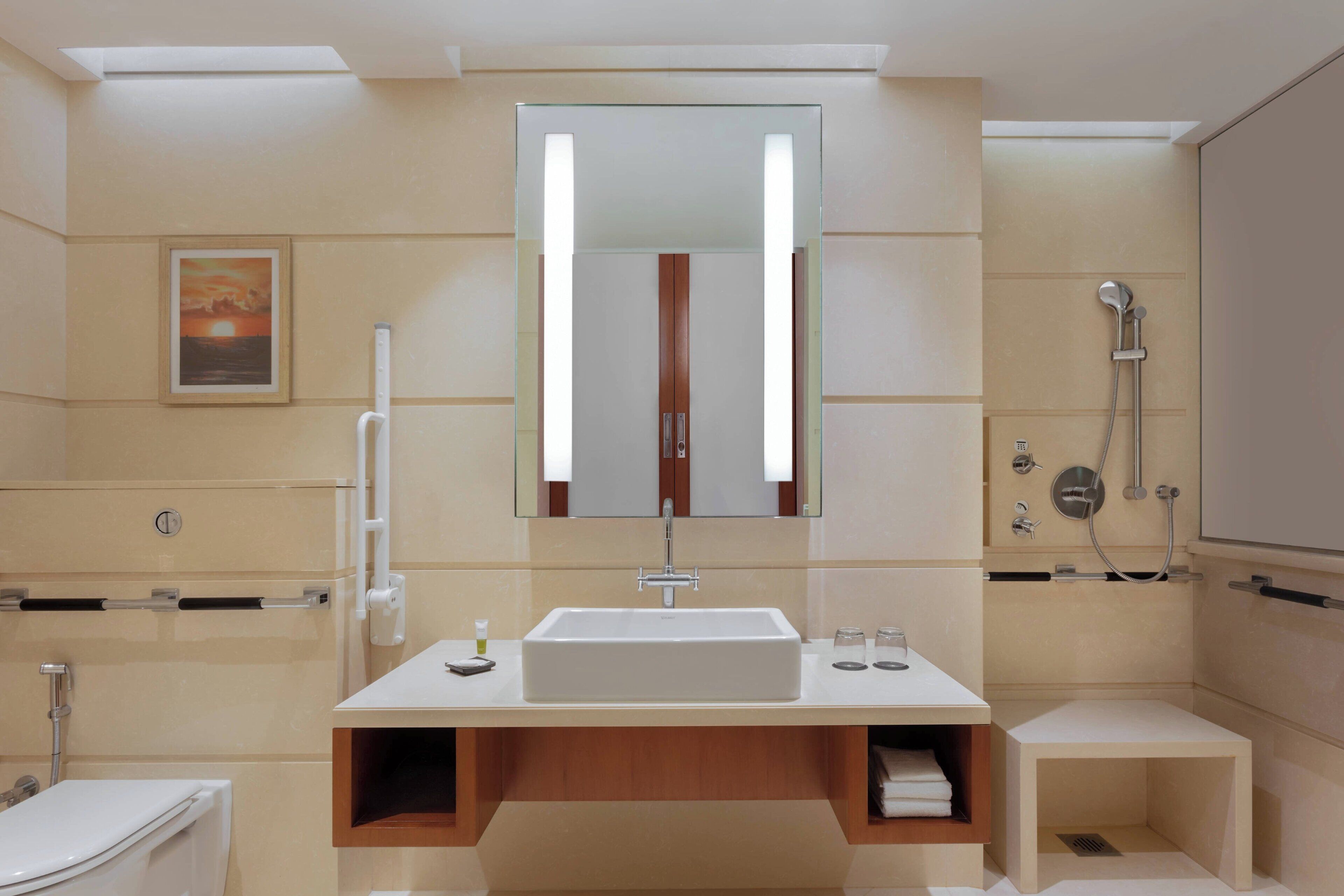 A modern bathroom with a large mirror, a sink, a shower, and a toilet.