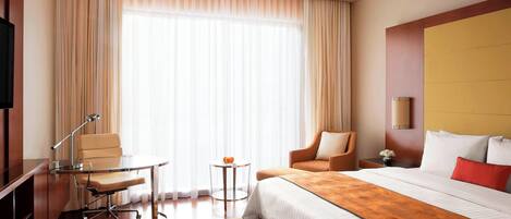 Una habitación de hotel con una cama grande, un escritorio con una silla, una mesita y un televisor.
