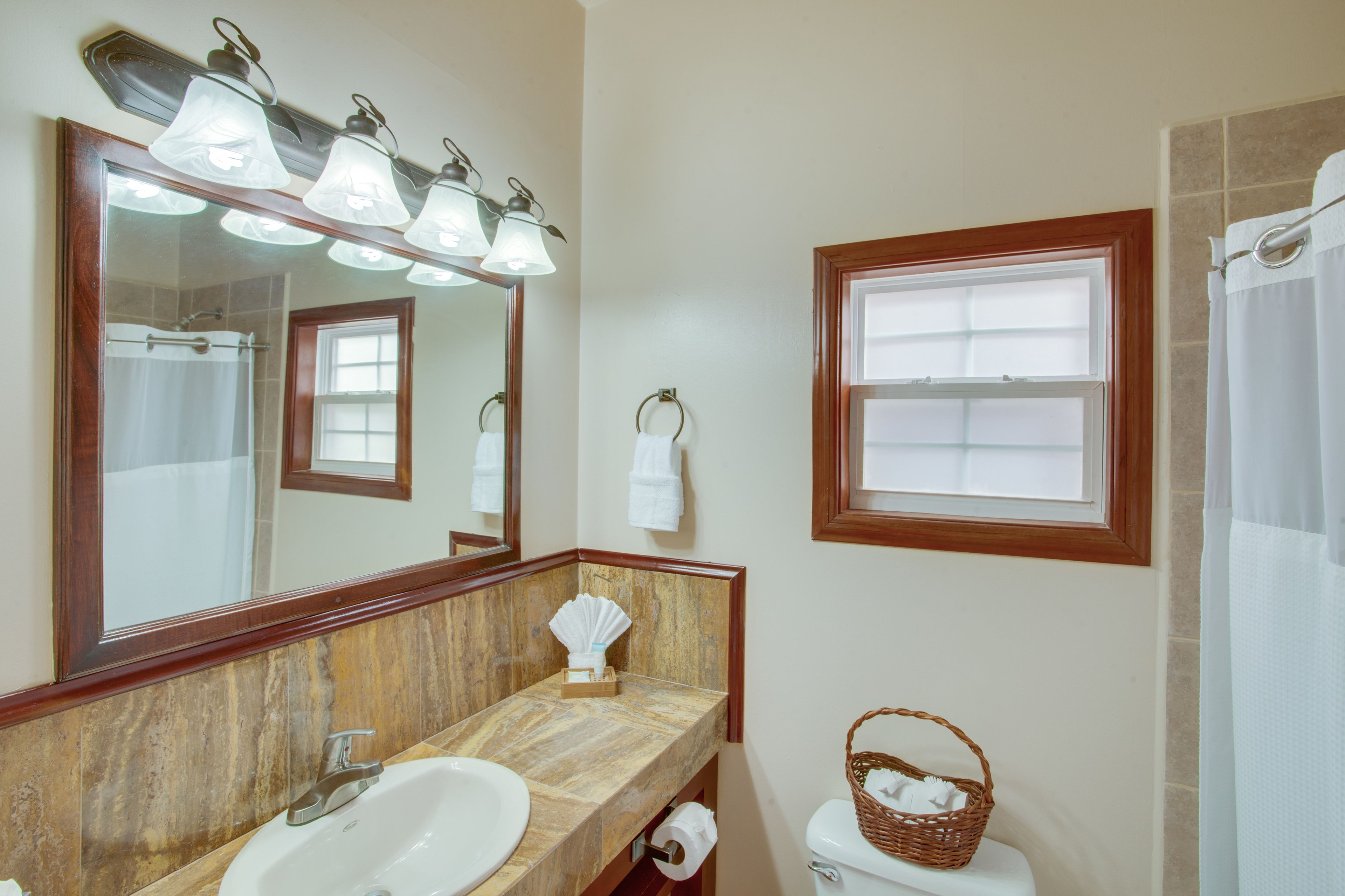 A bathroom with a large mirror, a sink, a toilet, and a shower curtain.