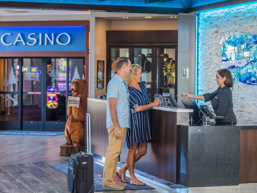 A reception desk with a staff member, a man and woman standing in front, and a bear mascot.