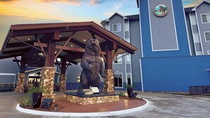 Un edificio con una estatua de oso en la fachada, un área techada y un revestimiento azul.
