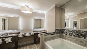Un bagno moderno con uno specchio grande, due lavabi, una vasca da bagno e un pavimento in legno.