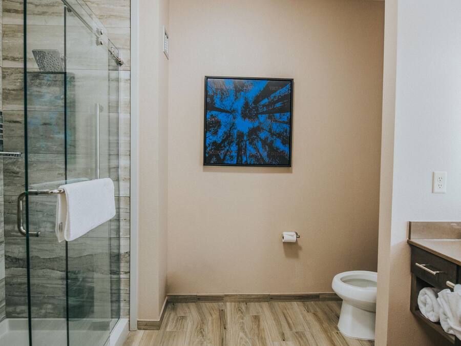 Et moderne badeværelse med en glasbrusekabine, toilet og håndvask med håndklædestang.