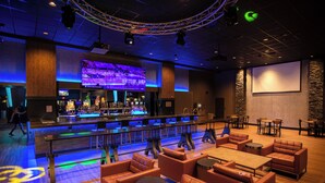 Zona de bar con asientos, una pantalla grande y una pantalla de proyección.