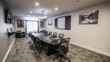 Un salón de conferencias con una larga mesa, sillas y piso alfombrado.