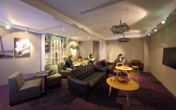 Un salon moderne comprenant un canapé, des fauteuils, une table basse et une bibliothèque.