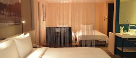 A hotel room with a large bed, a desk, a TV, and a bathroom with a mirror and sink.