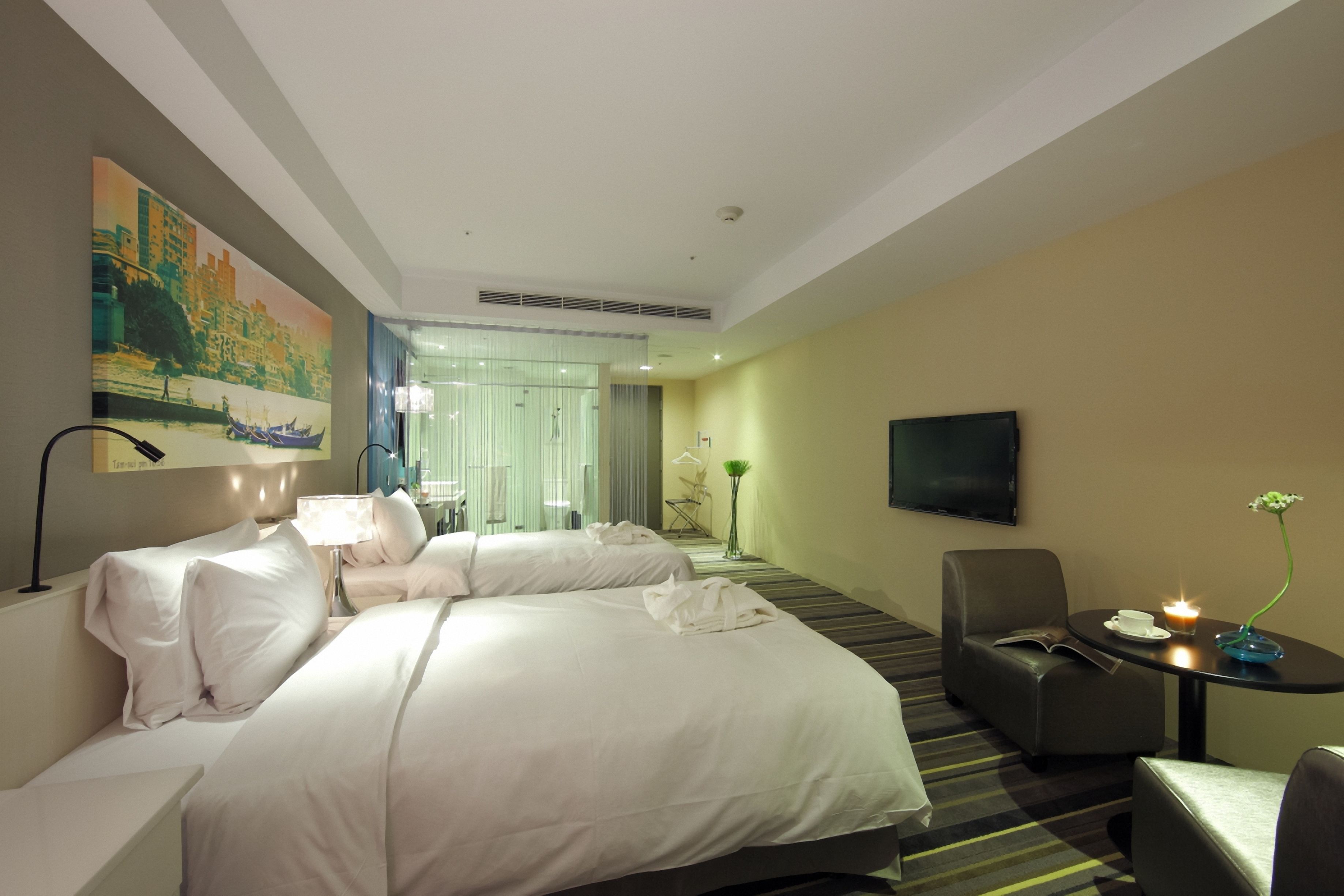 A hotel room with two beds, a TV, a desk with a lamp, and a painting on the wall.
