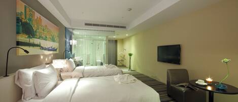 A hotel room with two beds, a TV, a desk with a lamp, and a painting on the wall.