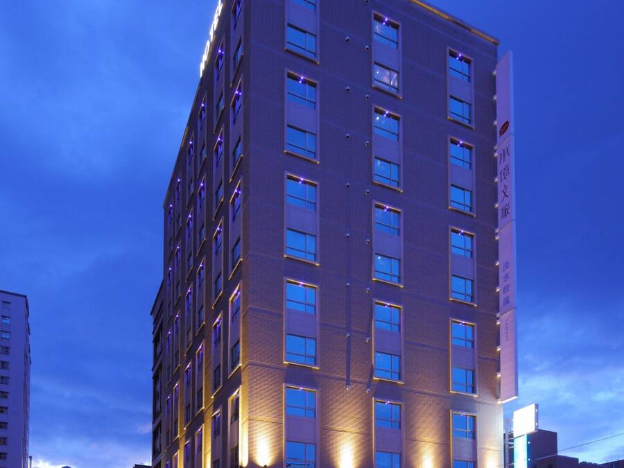 A multi-story hotel with a modern design, featuring a prominent entrance and a large outdoor seating area.