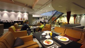 A modern restaurant with leather seating, a counter with food items, and a staircase leading to an upper level.