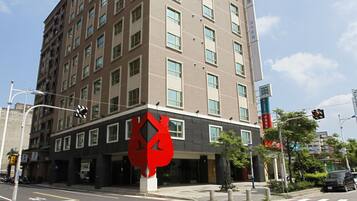 A multi-story hotel with a modern design, featuring a prominent red sculpture in front.