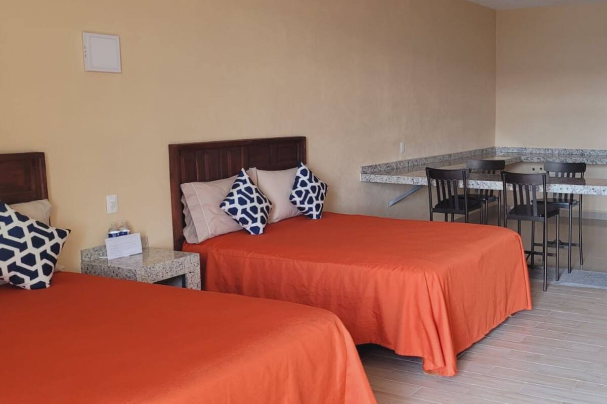 Una habitación de hotel con dos camas, una kitchenette pequeña y un comedor.