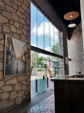 Un interno moderno con pareti in pietra, un'ampia porta a vetro che dà sull'esterno e una fotografia incorniciata appesa al muro.