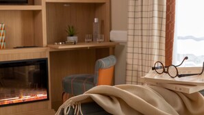 A cozy living room with a fireplace, a comfortable armchair, a small table with a plant, and a window with curtains. - Hôtel Sleeping Belle - Gare de Lyon Bastille (Paris)