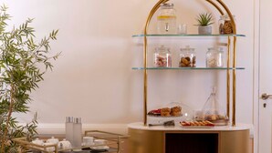 A buffet setup with glass jars and a gold-framed shelf, a potted plant, and a door in the background. - Hôtel Sleeping Belle - Gare de Lyon Bastille (Paris)