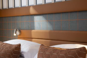 A hotel room with a modern headboard, a wall-mounted light, and two patterned pillows. - Hôtel Sleeping Belle - Gare de Lyon Bastille (Paris)