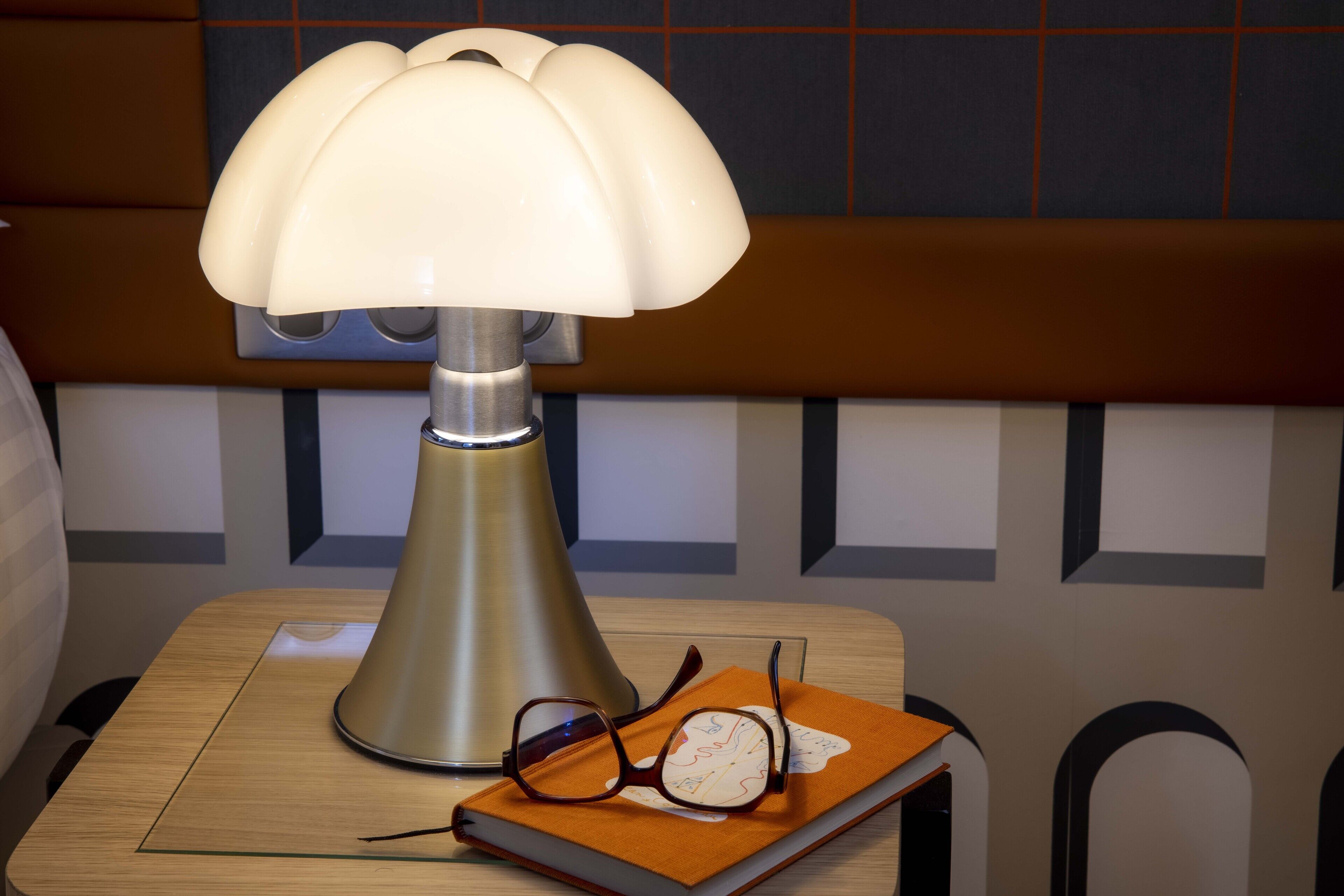 Una lámpara, gafas y un libro sobre una mesa de madera.