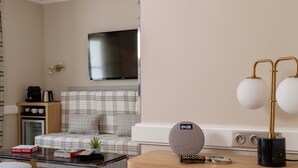 A modern living room with a sofa, a coffee table, a TV, and a lamp. - Hôtel Sleeping Belle - Gare de Lyon Bastille (Paris)