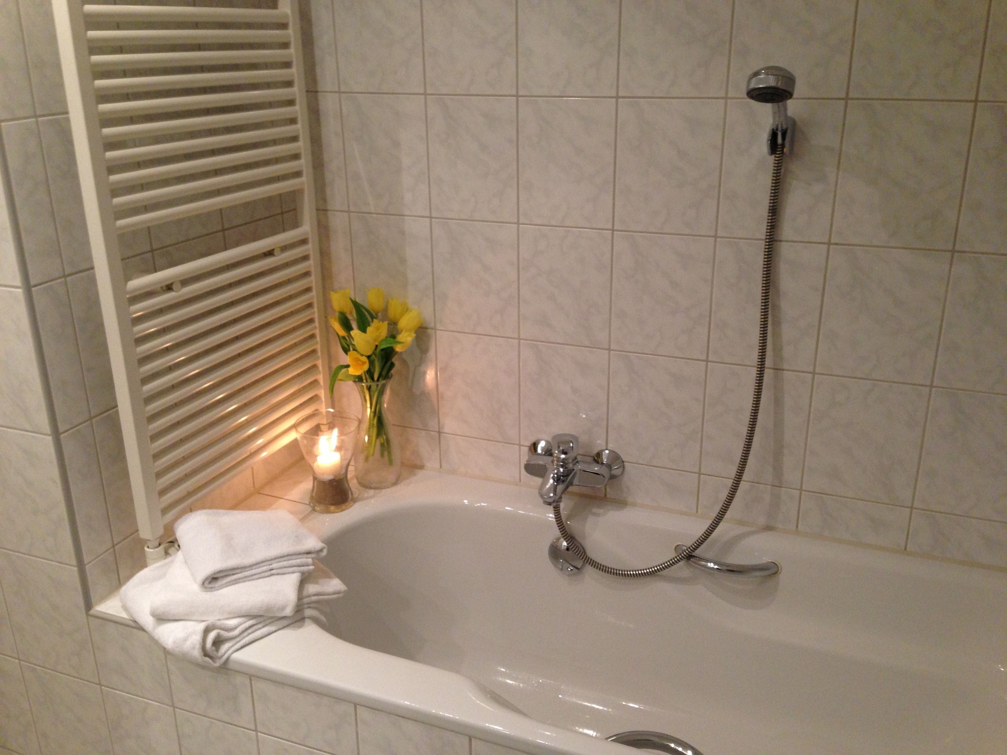 A bathroom with a bathtub, a shower, and a towel rack.