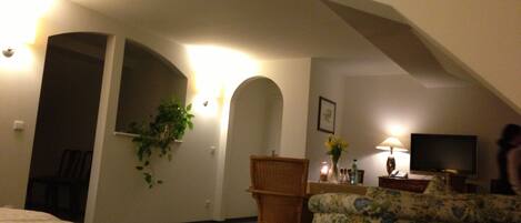 A bedroom with a bed, a chair, a television, and a plant.
