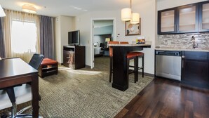 A compact hotel room with a dining area, kitchenette, and a TV. - Staybridge Suites Grand Forks by IHG (Grand Forks)