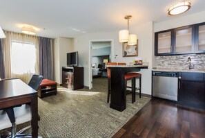 A compact hotel room with a dining area, kitchenette, and a TV. - Staybridge Suites Grand Forks by IHG (Grand Forks)