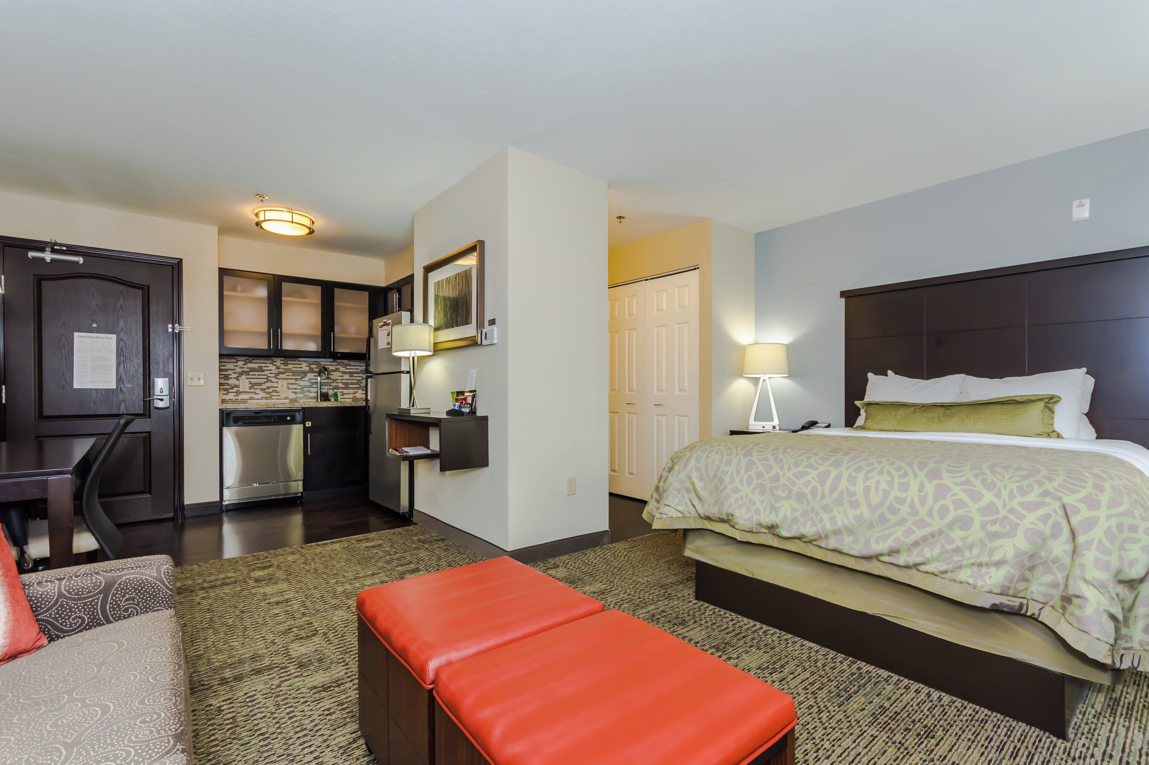 Een hotelkamer met een bed, een bureau, een kitchenette en een badkamer.