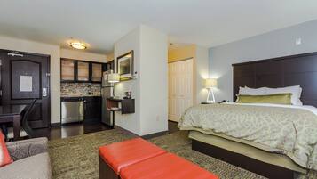Een hotelkamer met een bed, een bureau, een kitchenette en een badkamer.
