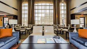 A spacious lobby with a large seating area, multiple tables, and a large window with curtains. - Staybridge Suites Grand Forks by IHG (Grand Forks)