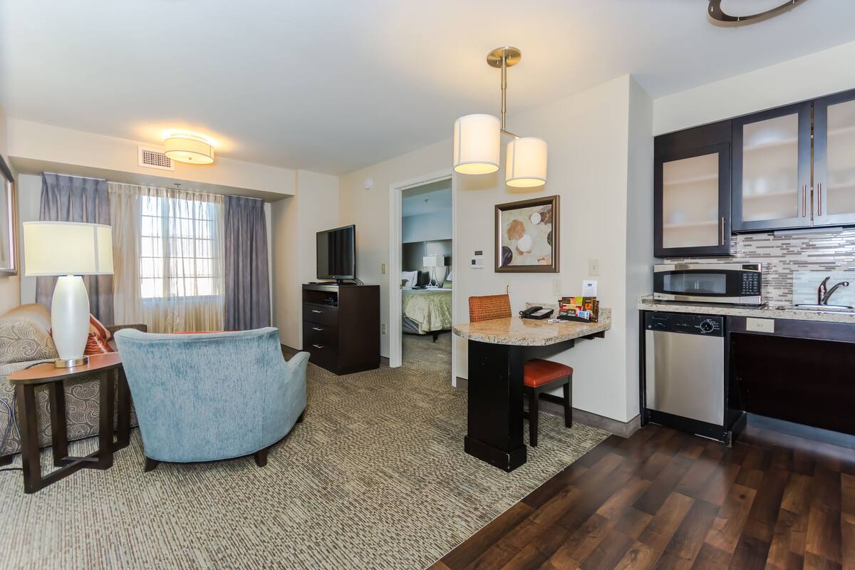 A compact hotel room with a kitchenette, a dining area, and a separate bedroom.