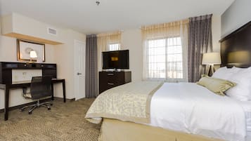 Une chambre d’hôtel avec un lit, un bureau, une télévision et une fenêtre avec des rideaux.