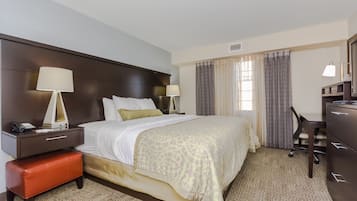 Habitación de hotel con una cama grande, dos mesitas de noche con lámparas, un escritorio y un aparador.