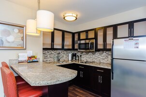 Una cocina moderna con encimeras de granito, electrodomésticos de acero inoxidable y armarios oscuros.