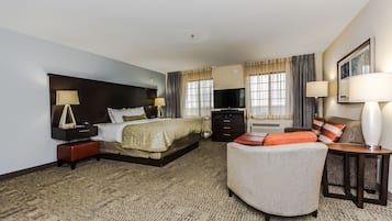 Una habitación de hotel con una cama, un sofá, un escritorio y un televisor.